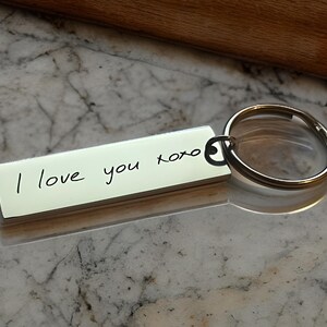 Op de afbeelding: Zilveren sleutelhanger met een rechthoekig label met de gravure "Ik hou van je xoxo".