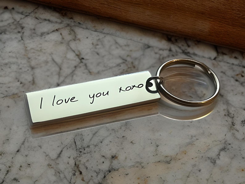 Op de afbeelding: Zilveren sleutelhanger met een rechthoekig label met de gravure "Ik hou van je xoxo".