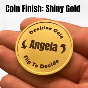 May include: Shiny gold coin with the text "Decision Coin" and "Flip To Decide" around the edge. The name "Angela" is in the center with arrows pointing left and right.