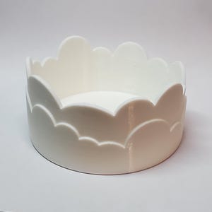 Puede incluir: Plato de cerámica blanco con un borde en forma de nube. El plato es redondo y tiene un acabado liso y brillante.