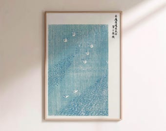 May include: Framed print featuring a blue and white Japanese woodblock print. The artwork depicts a stylized ocean scene with waves and small, white, cloud-like shapes. The print is in a light wood frame.