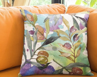 May include: A throw pillow featuring a watercolour design of olive branches and fruit. The pillow is on a bright orange sofa.