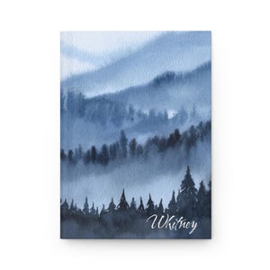 May include: A watercolor painting of a blue and gray forest with a misty background. The painting has the name "Whitney" written in white at the bottom.