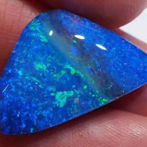 Könnte beinhalten: Ein blauer und grüner Opal-Edelstein in dreieckiger Form. Der Opal hat einen leuchtenden, irisierenden Glanz.
