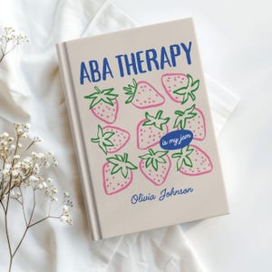 May include: A book with the title "ABA THERAPY" in blue, featuring pink strawberries with green leaves. The phrase "is my jam" is in a blue oval. The author's name, Olivia Johnson, is below the strawberries.