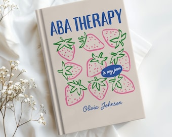 May include: A book titled "ABA THERAPY" in blue, decorated with pink strawberries and green leaves. A blue oval contains the words "is my jam". The author's name, Olivia Johnson, is printed below the strawberries.