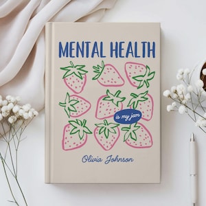 Puede incluir: Un diario beige con las palabras "MENTAL HEALTH" en azul y un patrón de fresas rosas con tallos verdes. La frase "is my jam" está en un óvalo azul, y el nombre "Olivia Johnson" está debajo.