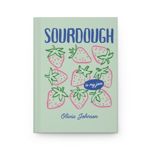 Puede incluir: Un diario verde claro con la palabra "SOURDOUGH" en azul y un patr&oacute;n de fresas rosas con hojas verdes. El texto "is my jam" est&aacute; en un &oacute;valo azul, y el nombre "Olivia Johnson" est&aacute; debajo.