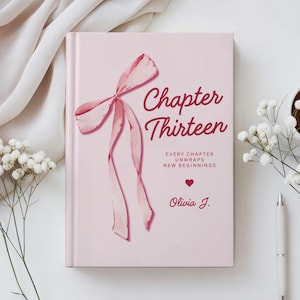 May include: A pink book cover with the title "Chapter Thirteen" in a cursive font, featuring a watercolor bow illustration. The text "Every Chapter Unwraps New Beginnings" and the author's name, Olivia J., are also visible.