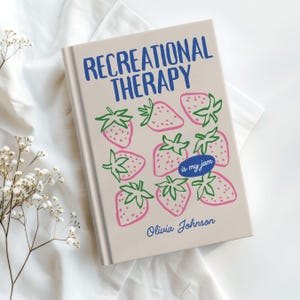 May include: A hardcover book titled "RECREATIONAL THERAPY" with a strawberry design. The cover features pink strawberries with green stems and the phrase "is my jam." The author's name, Olivia Johnson, is also on the cover.