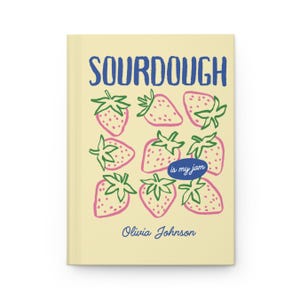Puede incluir: Un diario con una cubierta de color amarillo claro con la palabra "SOURDOUGH" en azul, encima de fresas rosas con tallos verdes. La frase "is my jam" est&aacute; en un &oacute;valo azul, y el nombre "Olivia Johnson" est&aacute; debajo.