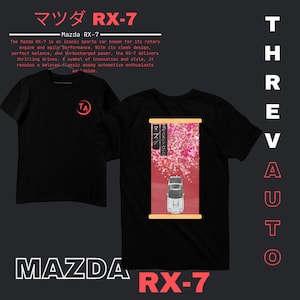 May include: Black t-shirt with a white Mazda RX-7 car graphic on the back. The car is driving through a pink cherry blossom design. The front of the shirt has a white circle with the letters "TA" in red.