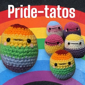 May include: A set of crocheted plushies in the shape of faces, each with a different color scheme representing the pride flag. The plushies are arranged on a rainbow background with the text "Pride-tatos" above them.
