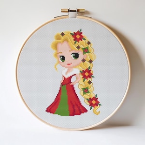 May include: Cross-stitch embroidery of a cartoon princess with long blonde hair adorned with red flowers. She wears a red dress with a green panel and a white collar. The embroidery is set in a round wooden hoop.