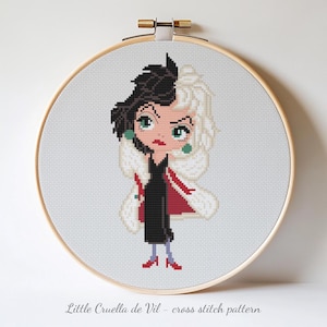 May include: Cross-stitch design of Cruella de Vil in a wooden embroidery hoop. The character has black and white hair, a black dress, and a red and white coat. The text "Little Cruella de Vil - cross stitch pattern" is at the bottom.