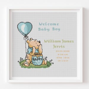 Könnte beinhalten: Gerahmtes Kreuzstichbild mit Winnie Puuh, der einen blauen herzförmigen Ballon hält. Der Text lautet "Welcome Baby Boy", der Name "William James Jervis", Geburtsdatum, Uhrzeit, Gewicht (3.0 kg) und Länge (49.5 cm). Der Honigtopf sagt "Happy Birthday".