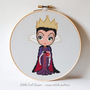 Könnte beinhalten: Kreuzstichmuster der bösen Königin in einem hölzernen Stickrahmen. Die Zeichentrickfigur trägt eine goldene Krone, lila und rote Roben und hält einen roten Apfel. Der Text "Little Evil Queen - cross stitch pattern" steht unten.