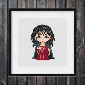 May include: A framed cross-stitch of a cartoon woman with black hair, blue eyes, and a red dress. She wears a dark green cape and gold jewelry. The artwork is set against a white background and framed in black.