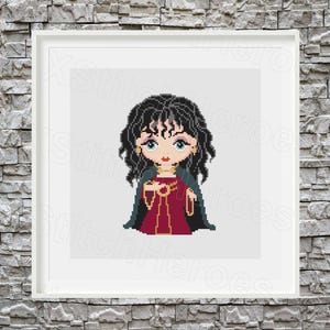 May include: A framed cross-stitch of a cartoon woman with black curly hair, blue eyes, and a red dress. She wears a dark green cape and gold jewelry. The artwork is displayed in a white frame against a gray brick wall.