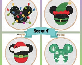 May include: Set of 4 cross-stitch hoops featuring Mickey Mouse designs. Each hoop has a wooden frame and a white background. Designs include Mickey with Christmas lights, an elf hat, a Santa hat, and a green snowflake and tree design.