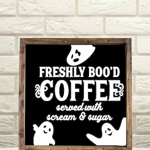 May include: A black framed sign with white text that reads "Freshly Boo'd Coffee served with scream & sugar". There are three white ghost silhouettes on the sign.