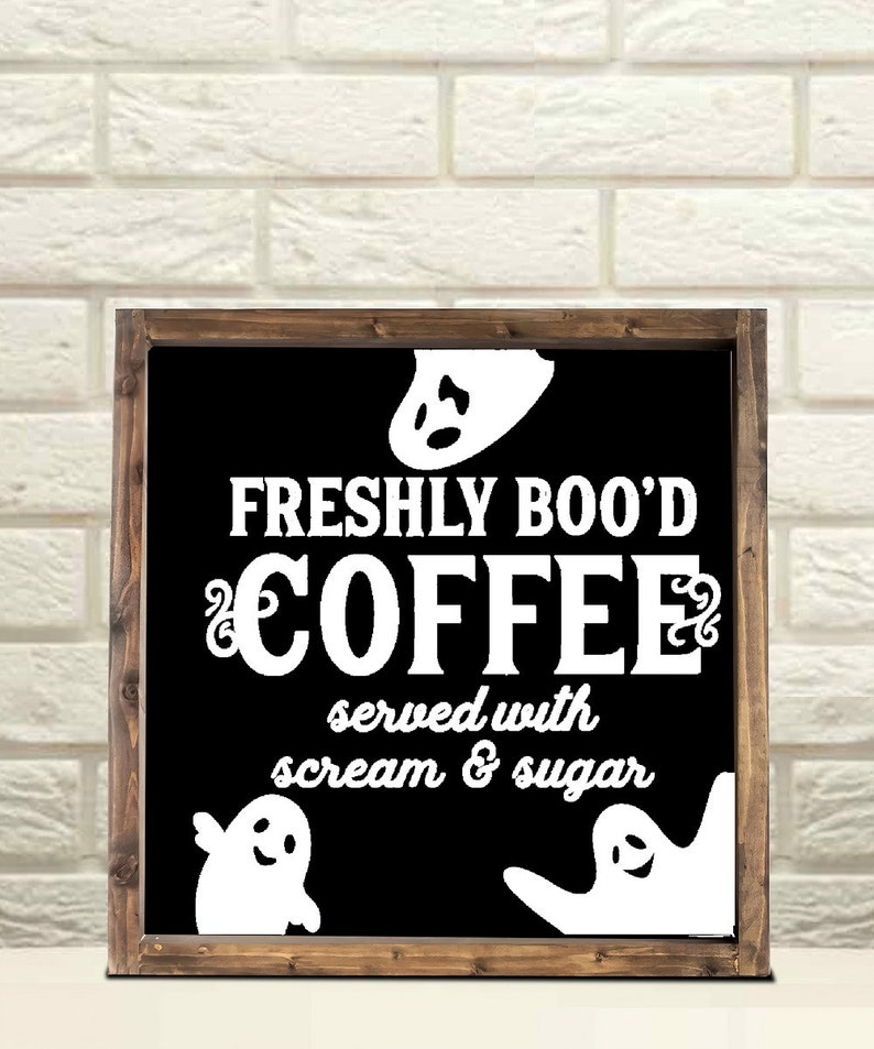 May include: A black framed sign with white text that reads "Freshly Boo'd Coffee served with scream & sugar". There are three white ghost silhouettes on the sign.