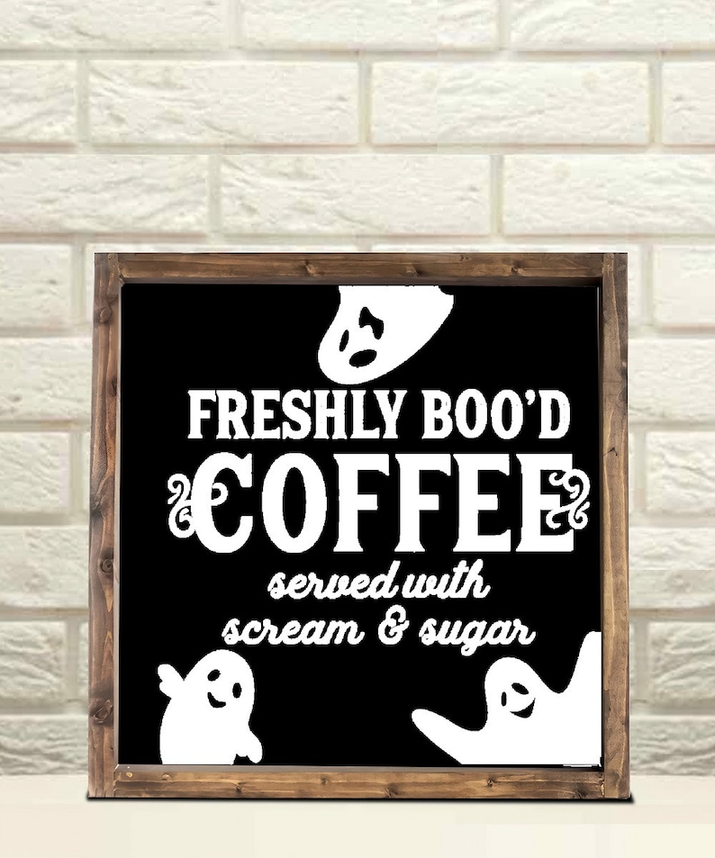 May include: A black framed sign with white text that reads "Freshly Boo'd Coffee served with scream & sugar". There are three white ghost silhouettes on the sign.