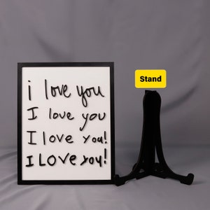 May include: A black framed dry erase board with the words "i love you" written on it four times in black marker. The board is standing on a black easel with a yellow label that says "Stand".