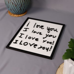 May include: A white framed dry erase board with the words "I love you" written on it four times in black marker.