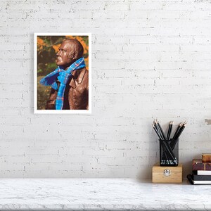 ‘Hap Up, Rabbie!’ art print, A4 size, unframed, shown on a wall. A statue of Scots bard Robert (Rabbie) Burns with a colourful scarf wrapped around it.