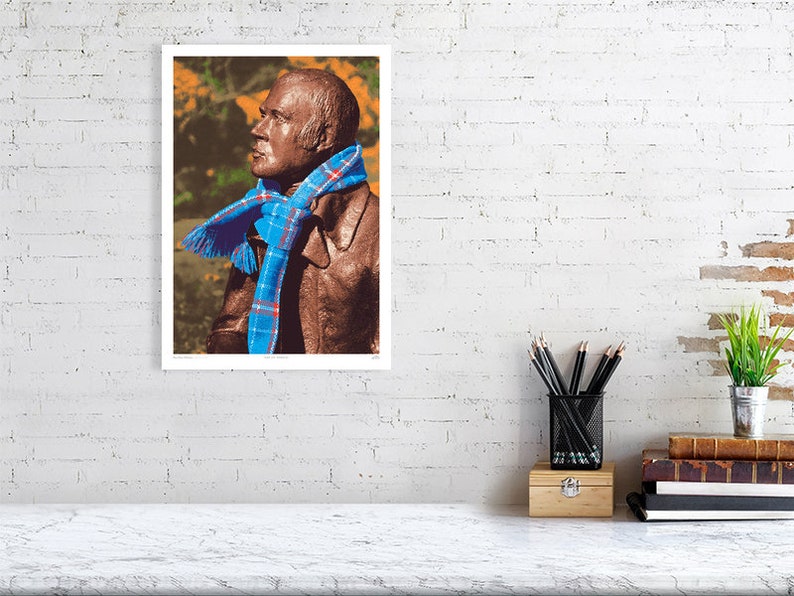 ‘Hap Up, Rabbie!’ art print, A3 size, unframed, shown on a wall. A statue of Scots bard Robert (Rabbie) Burns with a colourful scarf wrapped around it.