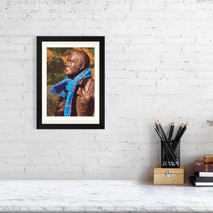 ‘Hap Up, Rabbie!’ art print, A4 size, mounted and framed, shown on a wall. A statue of Scots bard Robert (Rabbie) Burns with a colourful scarf wrapped around it.