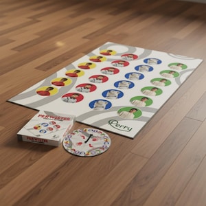 Può includere: Un set di giochi da tavolo con un tabellone bianco con cerchi colorati con immagini di persone. Il gioco include una scatola con l'etichetta "PERWISTER" e una trottola. Il tabellone ha il nome "Perry" stampato.