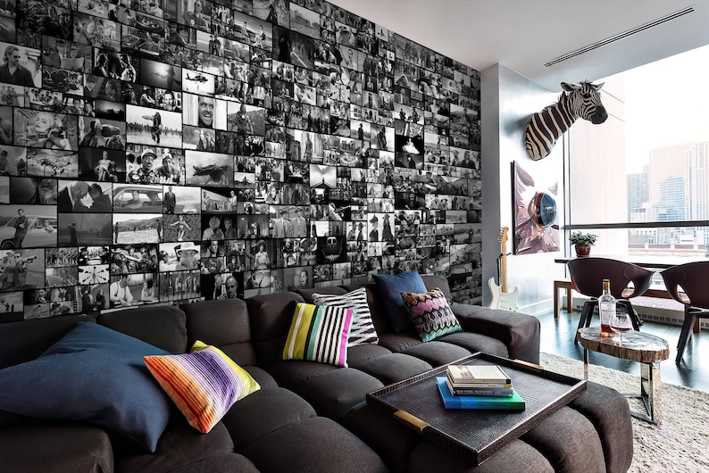 Può includere: Un soggiorno moderno con un divano angolare, un tavolino da caffè e una parete rivestita con una carta da parati a collage di foto in bianco e nero. La stanza ha grandi finestre con vista sullo skyline di una città.