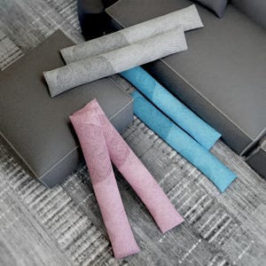 May include: Three decorative throw pillows with a lacy pattern. The pillows are in shades of gray, blue, and pink.