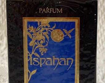 May include: A black box of Ispahan perfume with gold floral accents. The box has a blue center with the name "Ispahan" in gold script. The top of the box reads "PARFUM" and the bottom reads ".5 FL. OZ."