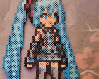 May include: A pixel art figure of a character with long, light blue pigtails, wearing a black outfit with gray accents. The figure is made of small, colorful beads. The text "thewade102" is in the bottom right corner.
