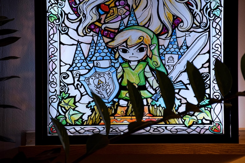 Puede incluir: Una ventana de vitral que representa a Link de la serie de videojuegos The Legend of Zelda. Link sostiene una espada y un escudo, y est&aacute; de pie frente a un castillo. La ventana est&aacute; enmarcada en negro y tiene un fondo azul claro.