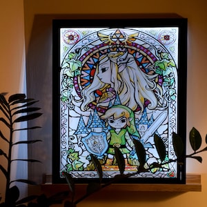 Puede incluir: Una obra de arte enmarcada de estilo vitral que representa una versi&oacute;n de dibujos animados de Link y Zelda de la serie de videojuegos The Legend of Zelda. La obra est&aacute; retroiluminada, creando un brillo colorido.