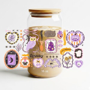 May include: A clear glass jar with a wooden lid, filled with a beige liquid. The jar is decorated with Halloween-themed stickers, including an owl, a cat, and a pumpkin. The text "frag Spooky" and "16 oz" are visible.