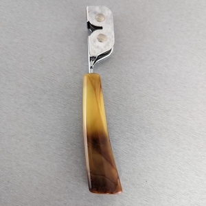 May include: A vintage knife sharpener with a brown and yellow plastic handle. The sharpener has two metal wheels.