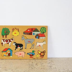 Puede incluir: Rompecabezas de animales de granja de madera con vaca, caballo, cerdo, perro, pato y gallina. El rompecabezas también incluye una casa, un granero y un árbol. Las piezas son de colores brillantes y están diseñadas para niños pequeños.