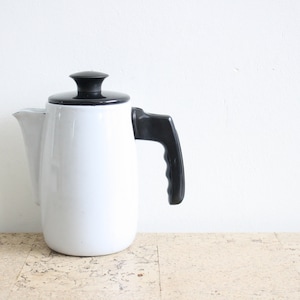 Può includere: Caffettiera in ceramica bianca con coperchio e manico neri. La caffettiera ha un design semplice ed è perfetta per preparare il caffè.