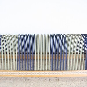 May include: A wooden record album storage rack with blue and green vinyl straps. The rack has a numbered scale on the front.
