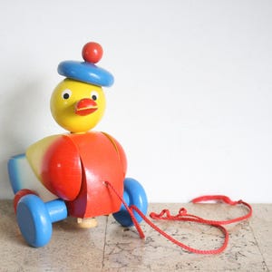 Puede incluir: Una taza de cerámica blanca con un asa negra y el texto "But First, Coffee" en negrita negra. La taza se encuentra sobre un fondo borroso, sugiriendo un ambiente acogedor.