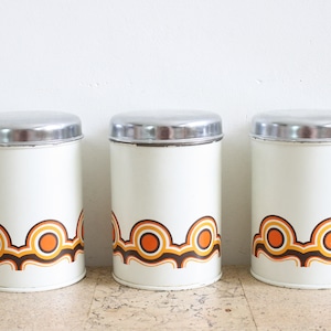 Three vintage metal tins with an orange and brown graphic print from Brabantia Holland