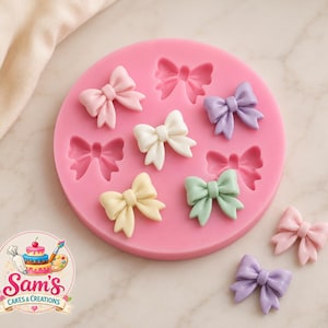 Puede incluir: Un molde de silicona rosa de forma redonda con múltiples cavidades en forma de lazo. Varios lazos terminados en colores pastel, incluyendo rosa claro, blanco, lavanda, amarillo pálido y verde menta, están dispuestos sobre y alrededor del molde. El logotipo Sam's Cakes & Creations es visible en la esquina inferior izquierda.