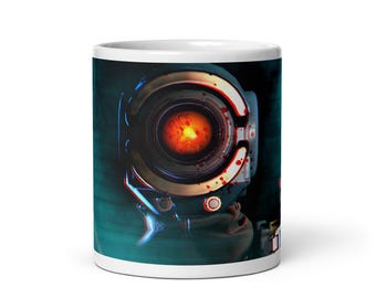 May include: White ceramic coffee mug featuring a detailed image of a robotic eye with a glowing orange center. The design has a futuristic, sci-fi aesthetic with dark teal and black accents.