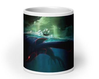 May include: White ceramic mug featuring a fantasy illustration of a sea creature with glowing red accents swimming in dark blue water. A ship sails on the stormy sea under a green sky. The mug is a standard size.