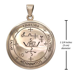 May include: A circular pendant with etched symbols and text, including "MICHAEL" and "ATHANATOS". The pendant is approximately 1 1/4 inches in diameter. It has a loop at the top for a chain.